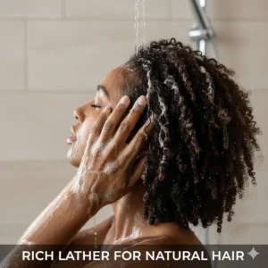 Woman lathering her natural hair with black soap shampoo during her wash day routine, showing the gentle but effective cleansing action.
