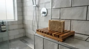 Oatmeal bar soap for combination skin placed on a bamboo shower dish in a tiled bathroom